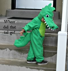 a toddler in a green alligator costume standing on steps with the caption where did that tail go?