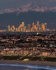 the city lights shine brightly in front of snow capped mountains