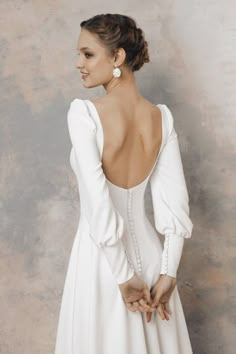 a woman in a white dress with her back turned to the camera and wearing earrings