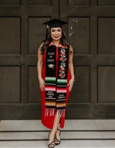 a woman wearing a graduation cap and gown standing in front of a garage door with her hands on her hips