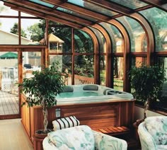 an indoor hot tub in the middle of a room with lots of windows and plants