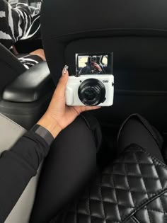 a person taking a photo in the back seat of a car with a digital camera