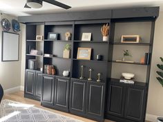 a living room with black bookcases and white rug on the floor in front of it