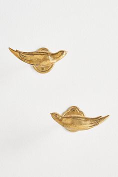 two gold bird shaped brooches sitting on top of each other