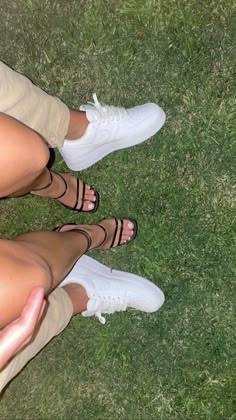 two people standing next to each other on top of a grass covered field with their feet in the air