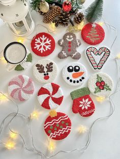 christmas ornaments on a white table with lights and pine cones in the background, including candy canes, snowman ornament