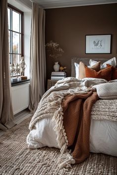 a bed with blankets and pillows on top of it in a bedroom next to a window