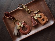 three leather keychains with tassels on a tray