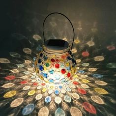 a lit up lantern sitting on top of a table covered in lots of different colored coins