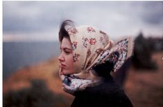 a woman wearing a headscarf and scarf on top of her head with mountains in the background