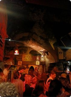 a group of people standing around in a room with lights on and signs hanging from the ceiling