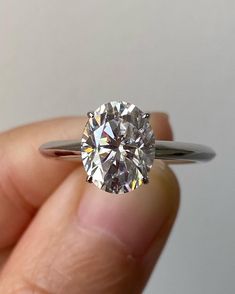 a close up of a person's hand holding a ring with a diamond in it