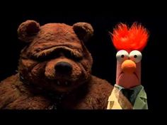 two stuffed animals are standing next to each other in front of a black background with an orange mohawk on its head