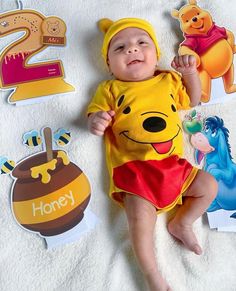 a baby in winnie the pooh costume laying next to some cutouts and stickers