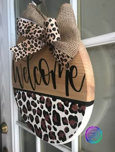 a welcome sign hanging on the front door with a leopard print bow and burlock