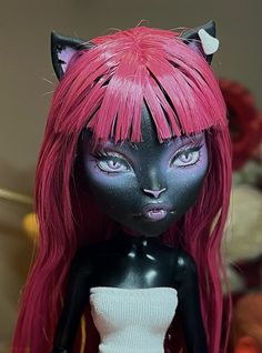 a black cat doll with pink hair and blue eyes