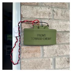 a sign that says front toward enemy on the side of a brick building with wires attached to it