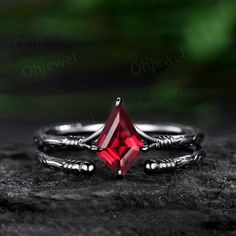 a close up view of a ring with a red stone in the middle and two claws on it