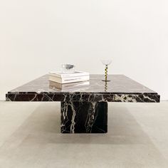 a marble coffee table sitting on top of a white floor next to a stack of books