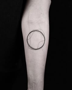 a black and white photo of a person's arm with a circle tattoo on it