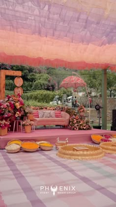 an outdoor area with tables and chairs covered in pink, yellow and purple cloths