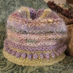 two knitted hats sitting on top of a bed