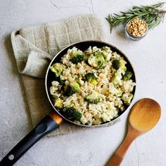 a bowl filled with rice and broccoli next to a wooden spoon on top of a towel