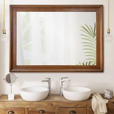 two white bowls sit on top of a wooden dresser under a large mirror