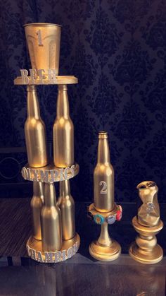 three golden beer bottles are stacked on top of each other and one has a cup in the middle