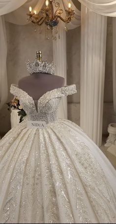 a wedding dress on display in front of a chandelier