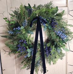 a wreath with blue berries and greenery hangs on a door