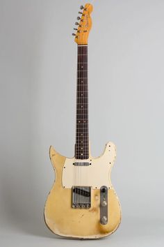 an old yellow electric guitar sitting on top of a table