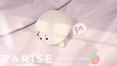 a white stuffed animal laying on top of a bed next to two pink stickers