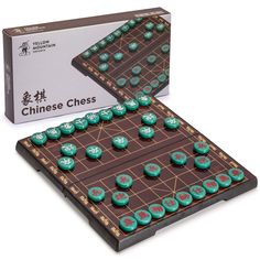 a chinese chess board with green and red dices on it's sides, in front of an open box