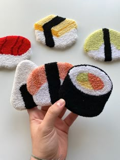 hand holding four sushi coasters in different colors