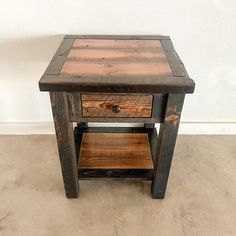 a small wooden table with one drawer on the bottom and two shelves below it, against a white wall