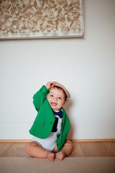 a baby in a suit and tie sitting on the floor with his hands behind his head