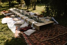 a long table is set up with plates and silverware on it in the grass