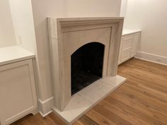 an empty room with a fireplace and white cabinets