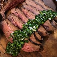 sliced steak with green garnish on wooden cutting board