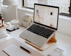 an open laptop computer sitting on top of a white desk next to a mouse and keyboard