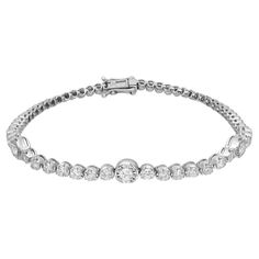 Introducing our stunning tennis bracelet, a timeless embodiment of classic elegance meticulously crafted in 18K white gold. Featuring dazzling round brilliant cut diamonds totaling 1.69 carats, with three diamonds set in prong settings for the illusion of larger stones. The bright white diamonds exhibit G-H color and SI clarity, ensuring remarkable brilliance. With a bracelet length of 7 inches and width of 5.5 mm, weighing 9.17 grams, it offers a substantial yet graceful adornment. Handmade wit Bracelet Tennis, Diamond Tennis Bracelet, American Modern, Tennis Bracelet Diamond, Tennis Bracelet, Round Brilliant Cut Diamond, A Bracelet, White Diamonds, Round Brilliant Cut