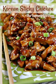 chicken with sesame seeds and green onions served on a green platter next to chopsticks