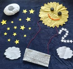 a blue blanket with yellow stars and a paper sun on it, next to a rock