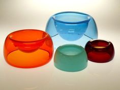 three different colored glass bowls sitting next to each other on top of a white table