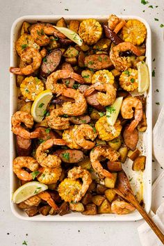 shrimp and potatoes in a casserole dish with lemon wedges