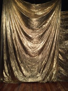 gold cloth draped over wooden floor in dark room