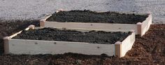 two wooden boxes filled with dirt next to water