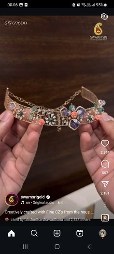 two hands holding up a tiara with jewels on it