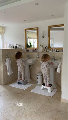 two young children standing on pedestals in a bathroom